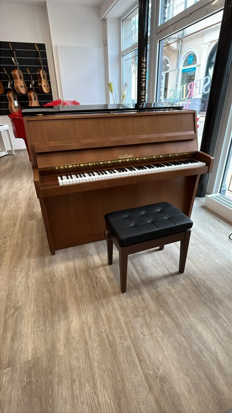 Ein braunes Schimmel Klavier in einem Raum mit Fenstern und Gitarren an der Wand.